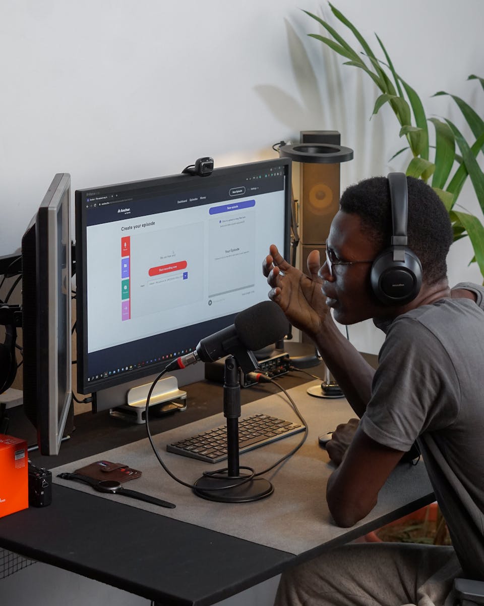 Man using headphones and microphone in home studio, engaging in podcast recording.